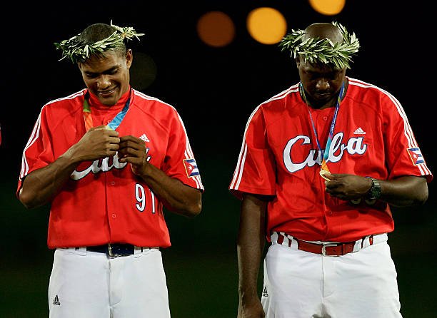 jogadores cubanos admirando a medalha de ouro